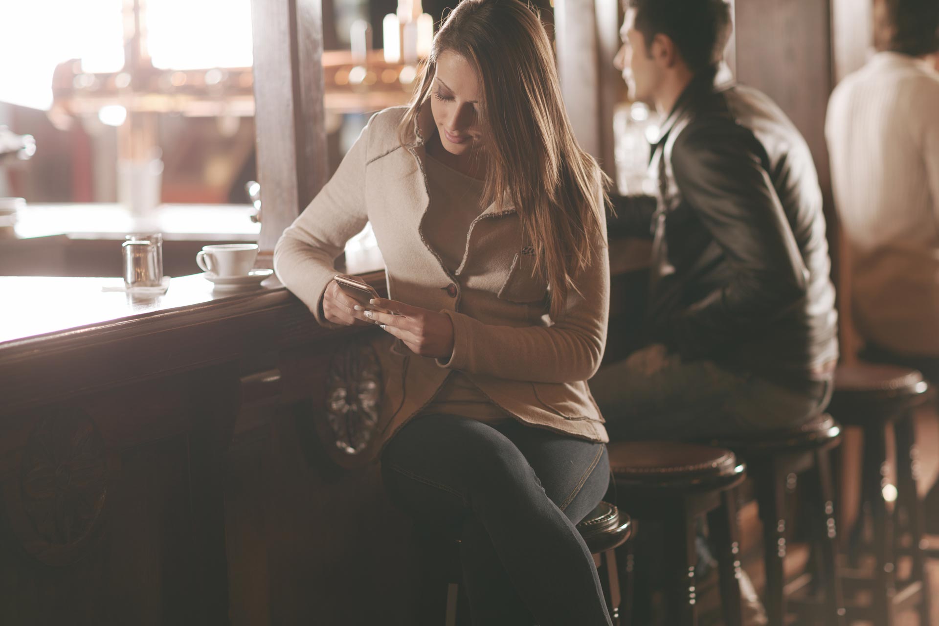 Schöne Frau an der Bar mit Smartphone